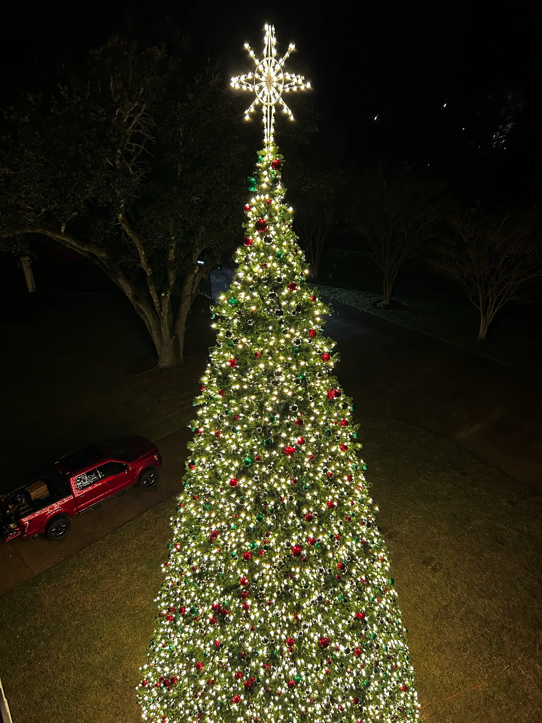 The upper tiers and illuminated star topper of a commercial Christmas tree at night.